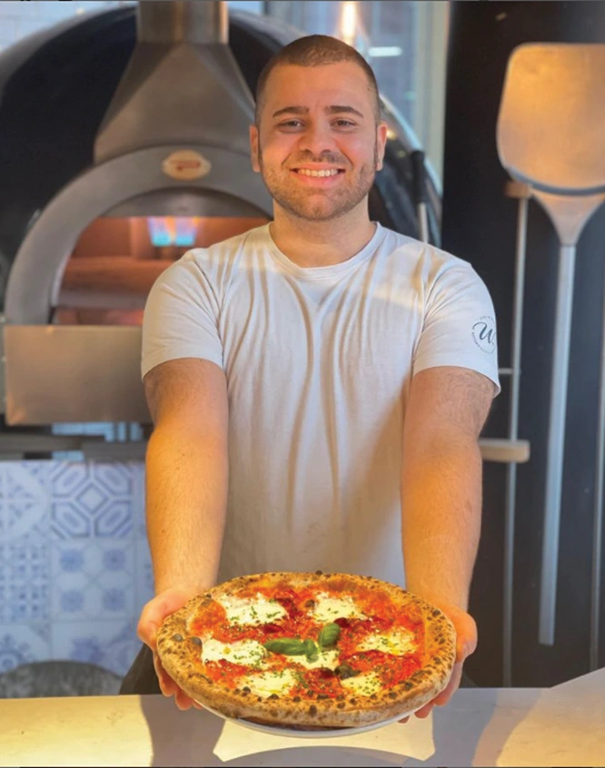 Pizzaiolo con pizza cotta in forno Pavesi professionale